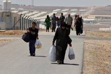 Newly-arrived Syrian refugees carry their belongings as they walk at Azraq refugee camp near Al Azraq area, east of Amman