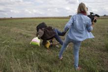 A Syrian refugee, Osama Abdul Mohsen, carrying his youngest son Zaid falls after being tripped by TV camerawoman Petra Laszlo (R) while trying to escape from a collection point in Roszke village, Hungary, September 8, 2015. PHOTO BY REUTERS/Marko Djurica