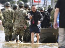 A local resident carrying his pet dog evacuates from an area flooded by the Abukuma river, caused by Typhoon Hagibis, in Motomiya, Fukushima prefecture, Japan, October 13, 2019, in this photo taken by Kyodo. PHOTO BY REUTERS/Kyodo