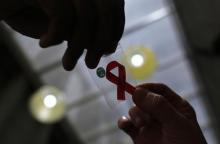 A nurse (L) hands out a red ribbon to a woman, to mark World Aids Day, at the entrance of Emilio Ribas Hospital, in Sao Paulo, December 1, 2014. PHOTO BY REUTERS/Nacho Doce