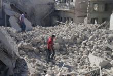Residents walk amidst rubble at a site hit by what activists said was a barrel bomb dropped by forces of Syria's President Bashar al-Assad, in the old city of Aleppo, May 26, 2015. PHOTO BY REUTERS/Abdalrhman Ismail