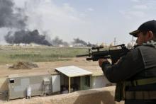 A member from the Iraqi security forces guards as smoke rises from Baiji oil refinery, north of Baghdad, Iraq, May 26, 2015. PHOTO BY REUTERS/Stringer