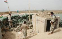 Members of the Kurdish security forces stand guard against Islamic State militants (background), behind sandbags on the Mullah Abdullah bridge in southern Kirkuk