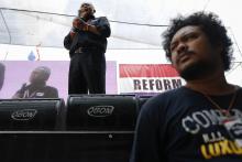 A security agent stands under a stage as protest leader Suthep Thaugsuban addresses anti-government protesters in their encampment in central Bangkok