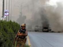 A member of Afghan security forces stands near the site of an attack as smoke billows, near the Afghan parliament in Kabul, Afghanistan, June 22, 2015. PHOTO BY REUTERS/Ahmad Masood