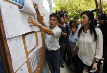Thai Prime Minister Yingluck Shinawatra (R) checks a list of voters' names before voting at a polling station in Bangkok