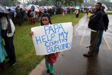 A woman holds a banner written "Papa Help My Country Burundi" before a mass by Pope Francis, as rain falls in Kenya's capital Nairobi, November 26, 2015. PHOTO BY REUTERS/Goran Tomasevic