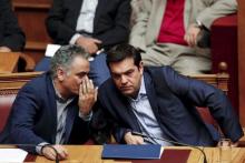 Greek Prime Minister Alexis Tsipras talks with Energy Minister Panos Skourletis (L) during a parliamentary session in Athens, Greece, July 22, 2015. PHOTO BY REUTERS/Yiannis Kourtoglou