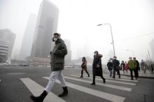 A man wearing a respiratory protection mask walks toward an office building during the smog after a red alert was issued for heavy air pollution in Beijing's central business district, China, December 21, 2016. PHOTO BY REUTERS/Jason Lee