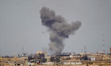 A plume of smoke rises above a building during an air strike in Tikrmt, March 27, 2015. PHOTO BY REUTERS/Thaier Al-Sudani