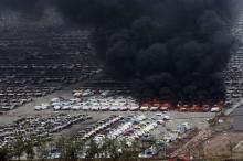 Smoke rises as damaged vehicles are seen burning near the site of Wednesday night's explosions, at Binhai new district in Tianjin, China, August 15, 2015. PHOTO BY REUTERS/Stringer
