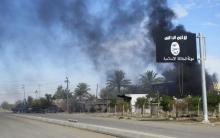 Smoke raises behind an Islamic State flag after in a file photo. PHOTO BY REUTERS/Stringer