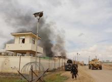 An Afghan security walks as smoke billows from a building after a Taliban attack in Gereshk district of Helmand province, Afghanistan, March 9, 2016. PHOTO BY REUTERS/Abdul Malik