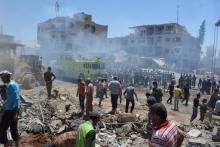 Smoke rises while people gather at a damaged site after two bomb blasts claimed by Islamic State hit the northeastern Syrian city of Qamishli near the Turkish border, Syria, July 27, 2016. PHOTO BY REUTERS/Rodi Said