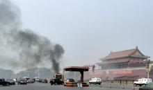 Vehicles travel along Chang'an Avenue as smoke raises in front of a portrait of late Chinese Chairman Mao Zedong at Tiananmen Square in Beijing