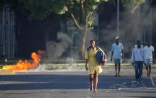Students walk past a burning barricade as clashes between students and police erupt at the University of the Western Cape during protests demanding free tertiary education in Cape Town, South Africa, October 19, 2016. REUTERS/Mike Hutchings