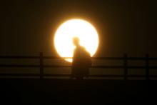 The sun can be seen rising as a man walks across Waterloo Bridge in central London, Britain, September 13, 2018. PHOTO BY REUTERS/Hannah McKay