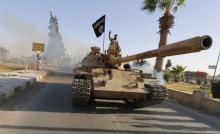 Militant Islamist fighters on a tank take part in a military parade along the streets of northern Raqqa province