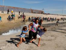 Maria Lila Meza Castro (C), a 39-year-old migrant woman from Honduras, part of a caravan of thousands from Central America trying to reach the United States, runs away from tear gas with her five-year-old twin daughters Saira Nalleli Mejia Meza (L) and Cheili Nalleli Mejia Meza (R) in front of the border wall between the U.S. and Mexico, in Tijuana, Mexico, November 25, 2018. PHOTO BY REUTERS/Kim Kyung-Hoon