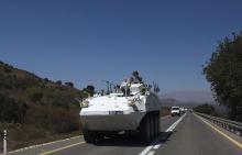 A member of the U.N. Disengagement Observer Force (UNDOF) rides atop an armoured vehicle near the Quneitra border crossing on the Israeli-occupied Golan Heights