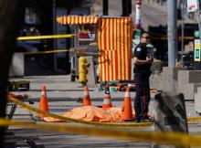 A police officer stands next to a victim of an incident where a van struck multiple people at a major intersection in Toronto's northern suburbs in Toronto, Ontario, Canada, April 23, 2018. PHOTO BY REUTERS/Carlo Allegri