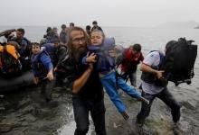 A volunteer carrying a Syrian refugee child off an overcrowded dinghy at a beach after the migrants crossed part of the Aegean Sea from Turkey to the Greek island of Lesbos, September 23, 2015. PHOTO BY REUTERS/Yannis Behrakis