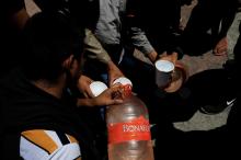 Central American migrants returned from the U.S. to Mexico under the Migrant Protection Protocols (MPP), drink water in Tijuana, Mexico, July 18, 2019. PHOTO BY REUTERS/Carlos Jasso