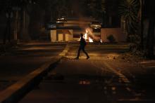 A woman walks past a burning barricade at Altamira Square in Caracas