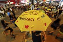 A woman sits under a yellow umbrella as pro-democracy protesters gather on a main street they occupy at Mongkok shopping district in Hong Kong, October 23, 2014. photo by REUTERS/Damir Sagolj