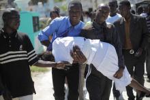 A woman who fainted is helped by others during the funeral for the victims of a Carnival stampede at a cemetery in Port-au-Prince, February 21, 2015. PHOTO BY REUTERS/Andres Martinez Casares