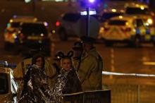 Two women wrapped in thermal blankets look on near the Manchester Arena, where U.S. singer Ariana Grande had been performing, in Manchester, northern England, Britain, May 23, 2017. PHOTO BY REUTERS/Andrew Yates