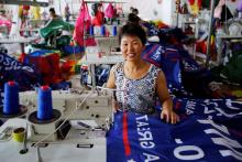 A worker poses for pictures as she makes flags for U.S. President Donald Trump's "Keep America Great!" 2020 re-election campaign at Jiahao flag factory in Fuyang, Anhui province, China, July 24, 2018. PHOTO BY REUTERS/Aly Song