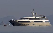 A luxury yacht speeds as Iranian migrants paddle an engineless dinghy trying to cross a part of the Aegean sea from the Turkish coast (seen in the background) to the Greek island of Kos, August 15, 2015. PHOTO BY REUTERS/Yannis Behrakis