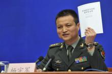 China's Ministry of Defence spokesman Colonel Yang Yujun speaks to journalists as he holds up the white paper on "The Diversified Employment of China's Armed Forces" during a news conference in Beijing