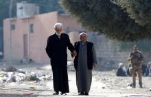 Two men hold hands as an Iraqi Special forces intelligence team searches for Islamic State fighters in Mosul, Iraq, November 27, 2016. PHOTO BY REUTERS/Goran Tomasevic