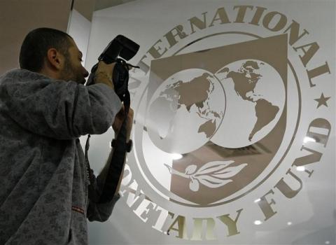 A photographer takes pictures through a glass carrying the International Monetary Fund (IMF) logo during a news conference. PHOTO BY REUTERS/Bogdan Cristel