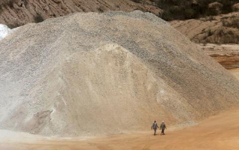 Workers walk past a pile of limestone at the Dangote Cement mine in a file photo. PHOTO BY REUTERS/Akintunde Akinleye