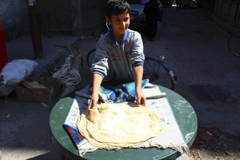 A boy makes bread in Duma neighbourhood, in Damascus