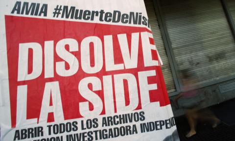 A woman walks behind a poster that reads "AMIA (Jewish community center). Nisman's death. Disolve the SIDE (Secretary of Intelligence)" in Buenos Aires, January 26, 2015. PHOTO BY REUTERS/Marcos Brindicci