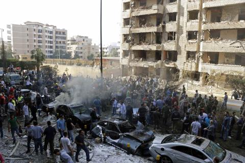 Soldiers, policemen and medical personnel gather at the site of explosions near the Iranian embassy (L) in Beirut