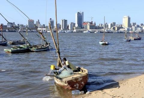 A fisherman cleans his boat beneath Maputo's skyline, Mozambique, August 15, 2015. PHOTO BY REUTERS/Grant Lee Neuenburg