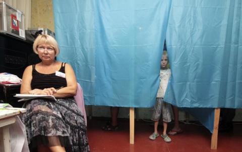 A boy looks out of a voting booth at a polling station in the Crimean port of Sevastopol