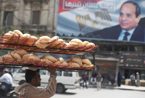 A man carries breads on his head along a busy street near a banner for Egypt's President Abdel Fattah al-Sisi from the campaign titled “Alashan Tabneeha” (So You Can Build It) after election results in Cairo, Egypt April 3, 2018. PHOTO BY REUTERS/Amr Abdallah Dalsh