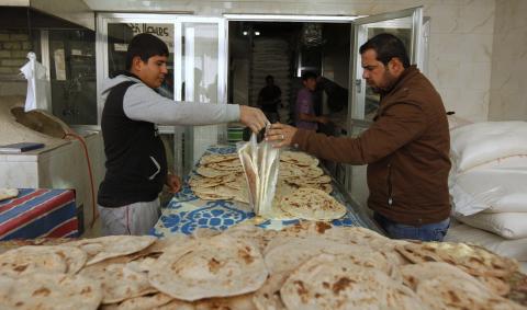 A customer (R) buys bread at a bakery in Baghdad, January 14, 2015. PHOTO BY REUTERS/Ahmed Saad
