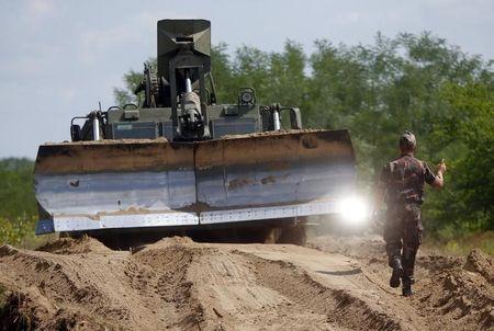 Hungarian army soldiers use a bulldozer as they prepare the land to build a fence along the Hungarian border with Serbia near Morahalom, Hungary, July 14, 2015. PHOTO BY REUTERS/Laszlo Balogh