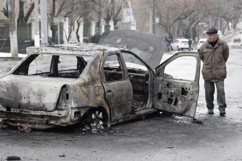 A man looks at a burnt car near a trolleybus stop in Donetsk, January 22, 2015. PHOTO BY REUTERS/Alexander Ermochenko