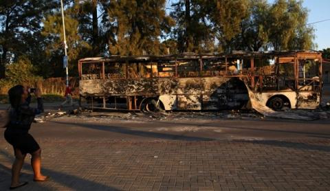 A women uses a cellphone to photograph the remains of a burnt out bus used to barricade roads by protesters in Atteridgeville a township located to the west of Pretoria, South Africa, June 21, 2016. PHOTO BY REUTERS/Siphiwe Sibeko