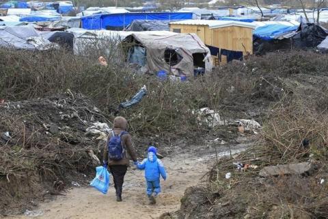 A migrant and her child walk in the southern part of a camp for migrants called the "jungle", in Calais, northern France, February 25, 2016. PHOTO BY REUTERS/Pascal Rossignol