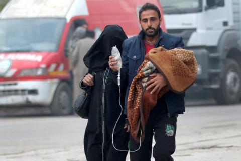 A man carries a child with an IV drip as he flees deeper into the remaining rebel-held areas of Aleppo, Syria, December 12, 2016. PHOTO BY REUTERS/Abdalrhman Ismail