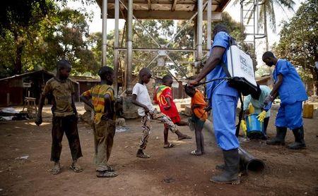 Children come forward to get their feet disinfected after a Red Cross worker explained that they are spraying bleach, and not spraying the village with the Ebola virus, in Forecariah, January 30, 2015, PHOTO BY REUTERS/Misha Hussain